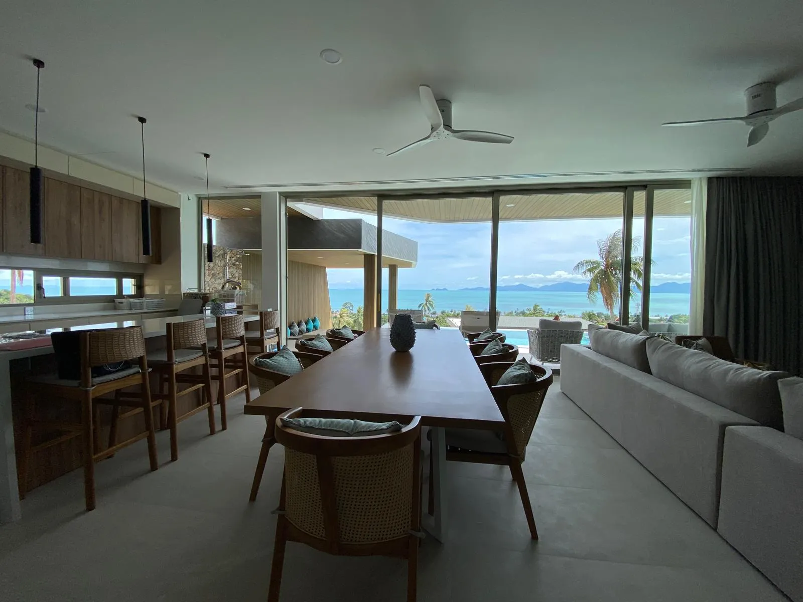 Long dining table through open doors to pool terrace and distant mountains, Lamai, Koh Samui